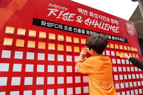 [크기변환]화성FC의 프로추진을 응원하는 어린이 팬이 메시지 보드에 응원문구를 붙이고 있다.jpg