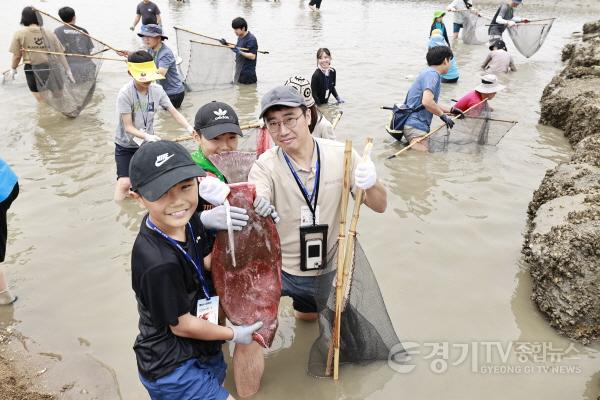 [크기변환]1-4. 화성 뱃놀이 축제의 ‘독살 체험’ 프로그램에 참여한 가족이 직접 잡은 물고기를 들고 환하게 웃고 있다.jpg