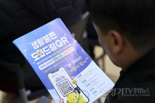 [크기변환]1-9. 화성특례시 2026년 신년인사회에 참석한 시민이 생활불편 도와드림QR 안내문을 살펴보고 있다.jpg